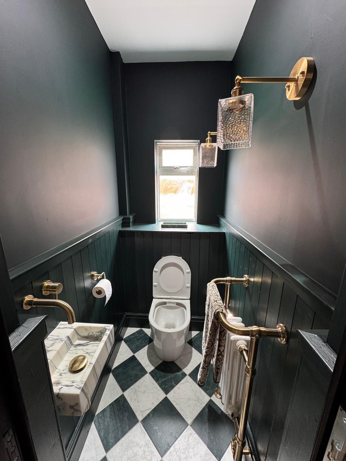 Cloakroom with dark green walls, panelling and a checkerboard floor