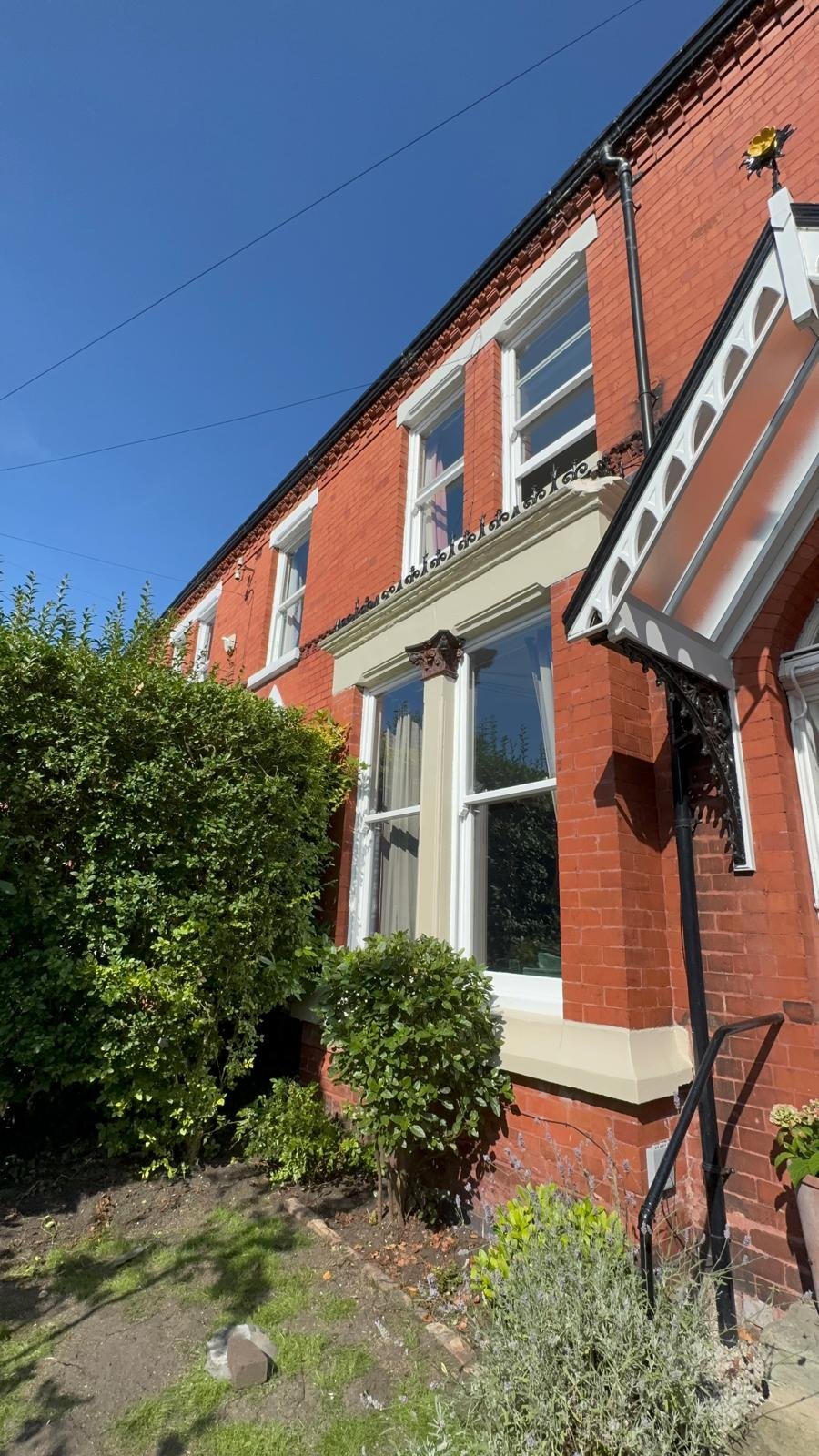 Red brick house with a white painted bay window and rendered detail
