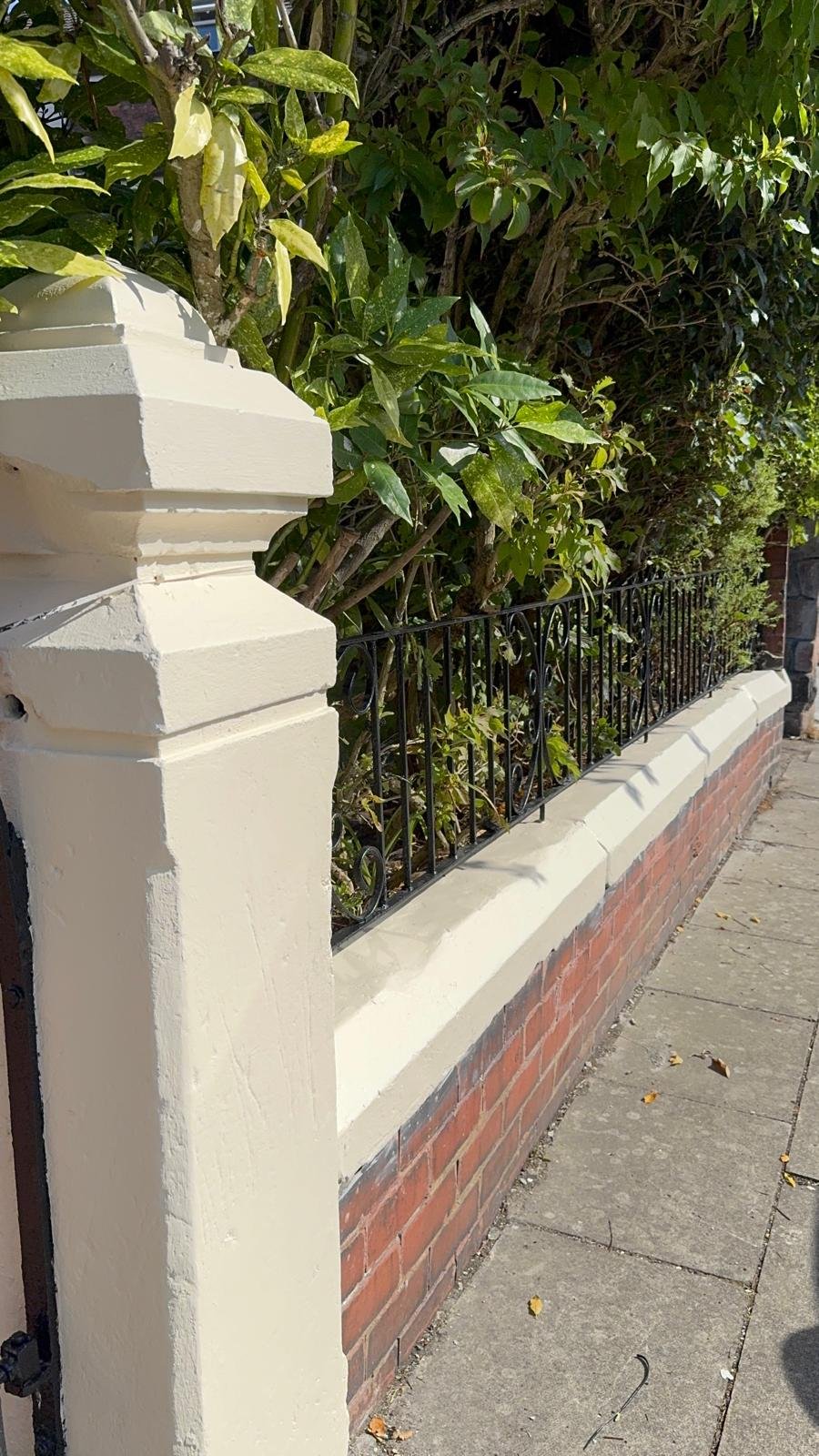 A garden wall finished in cream masonry paint above brickwork