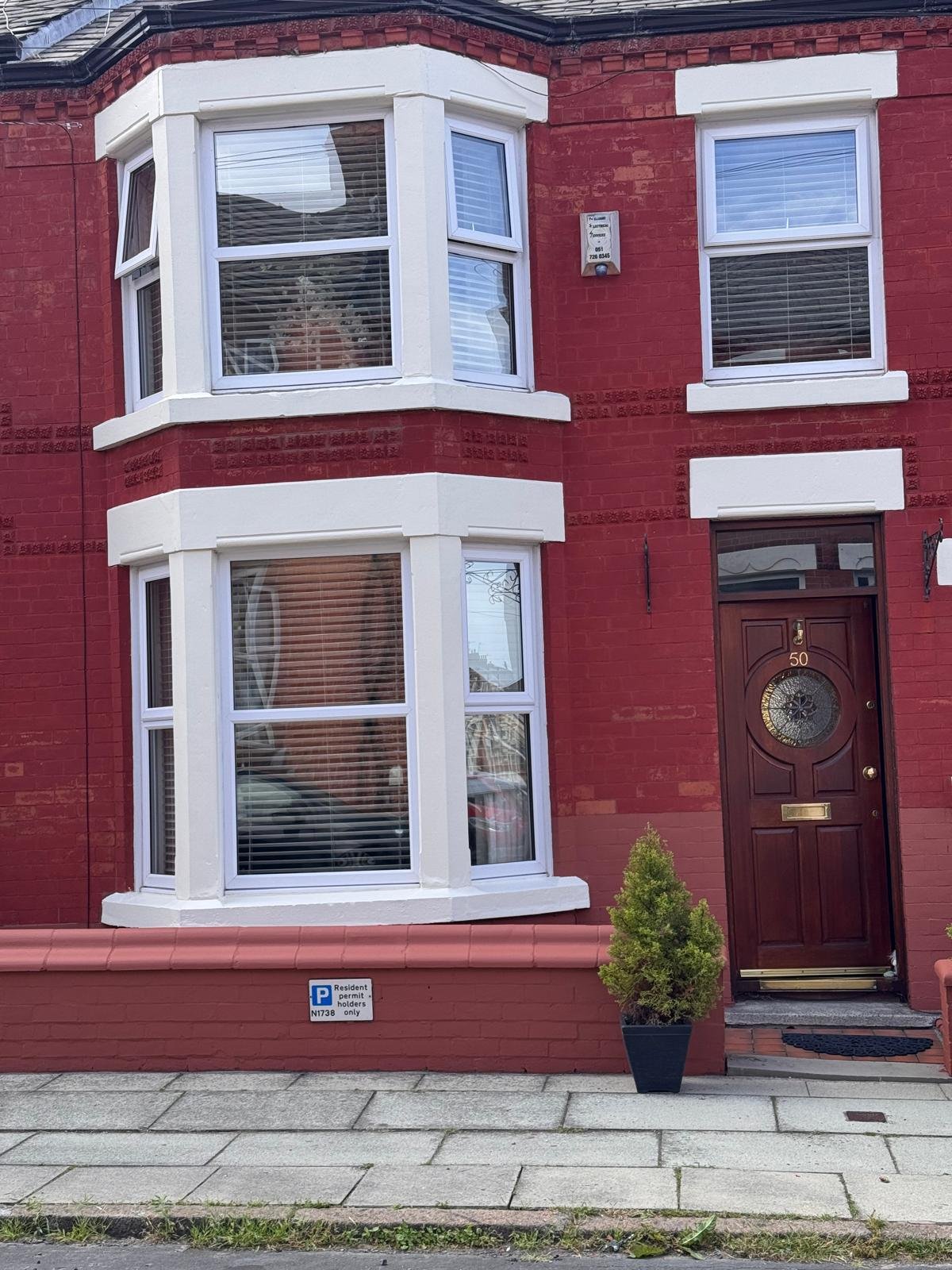 Red brick terrace with a white painted bay window and a maroon front door