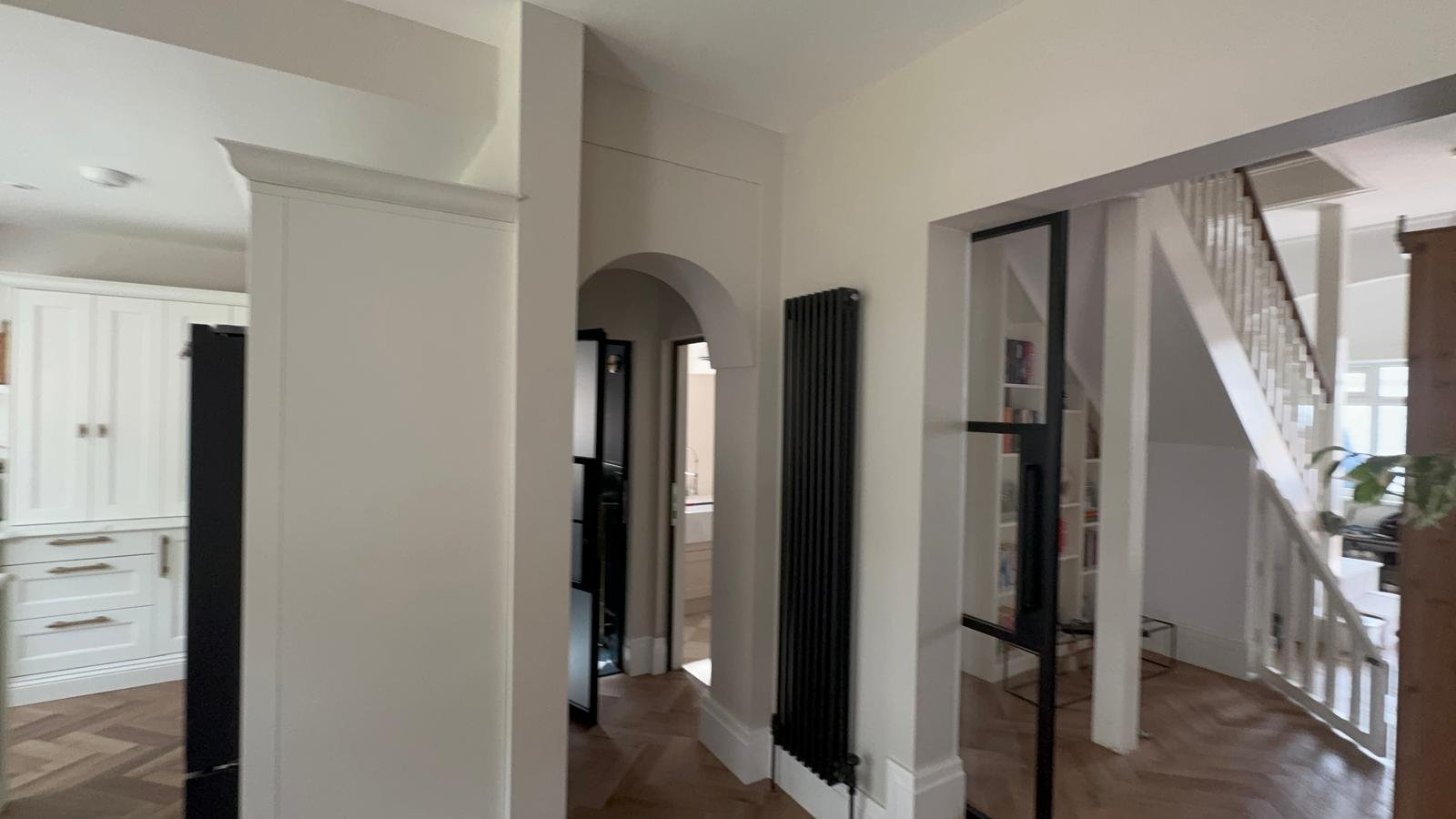 Hallway with white walls, black doors and an arched opening