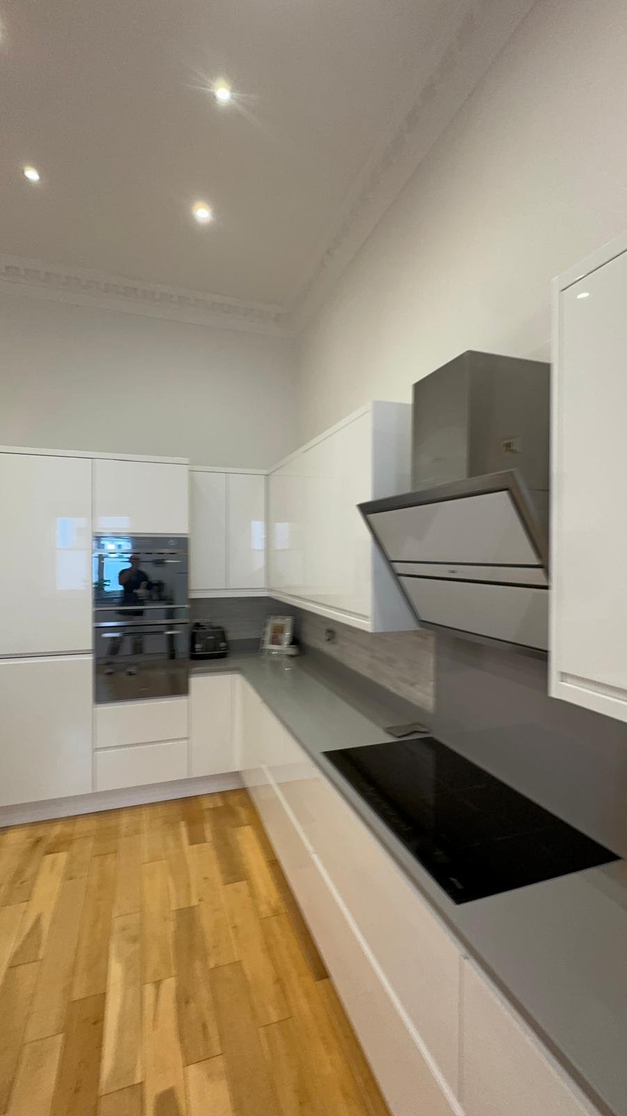 White galley kitchen with an extractor and dark worktop