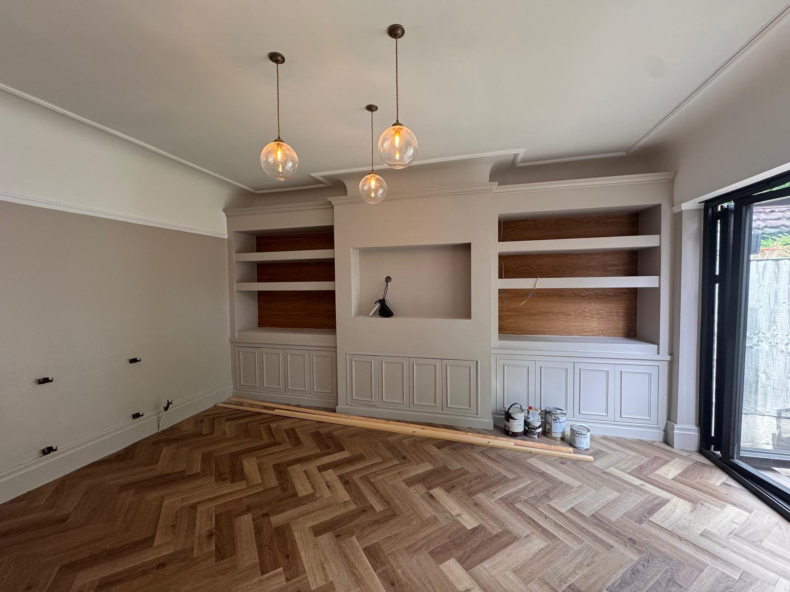 Living room with herringbone flooring and built in alcove cabinetry