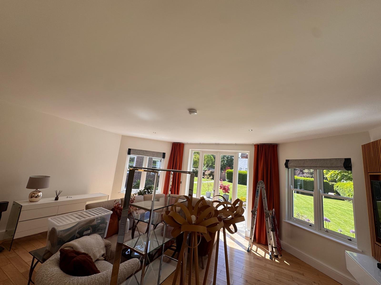 Living room with neutral walls, red curtains and garden doors