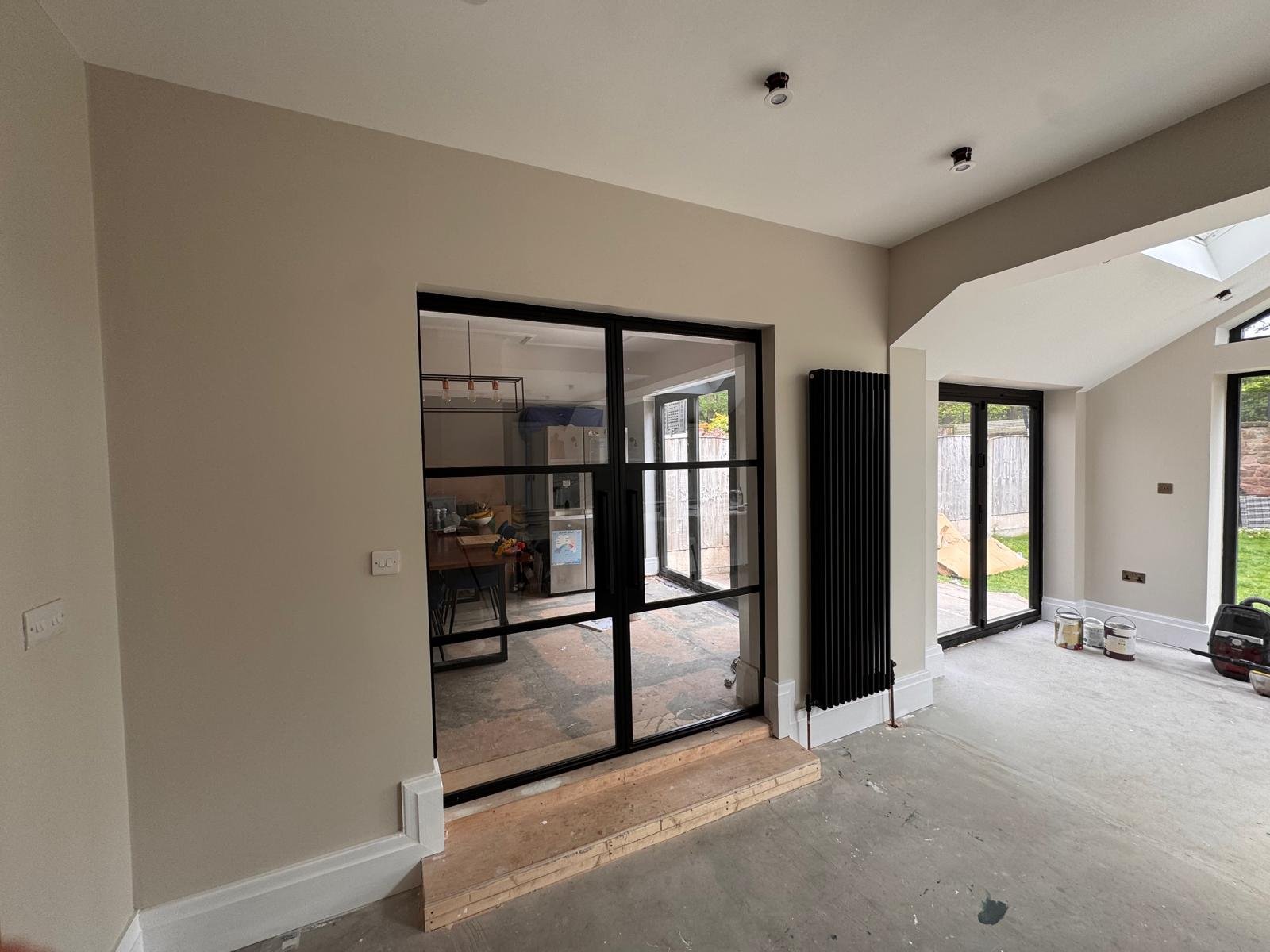 Open plan room with black Crittall style doors and neutral walls