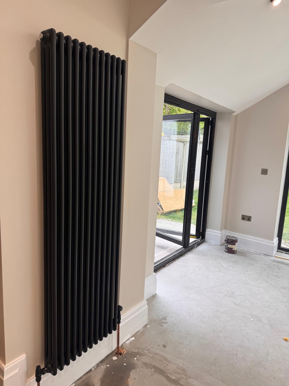Room with a tall anthracite column radiator and garden glazing